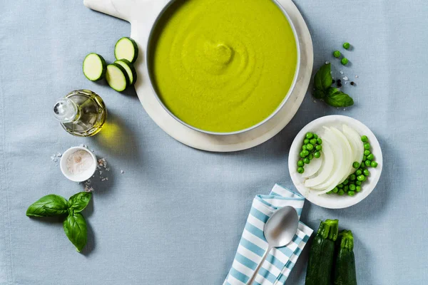 Mavi masa örtüsü üzerinde yeşil bezelye ve kabak kremalı çorba. sağlıklı beslenme