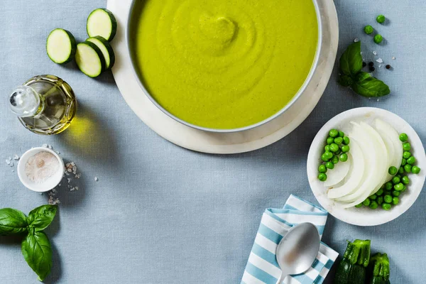 Mavi masa örtüsü üzerinde yeşil bezelye ve kabak kremalı çorba. sağlıklı beslenme