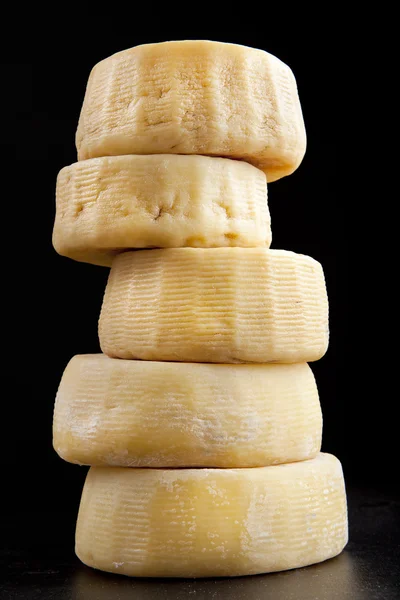 Några hela former av ost parmesan, en ovanpå den andra. på svart — Stockfoto