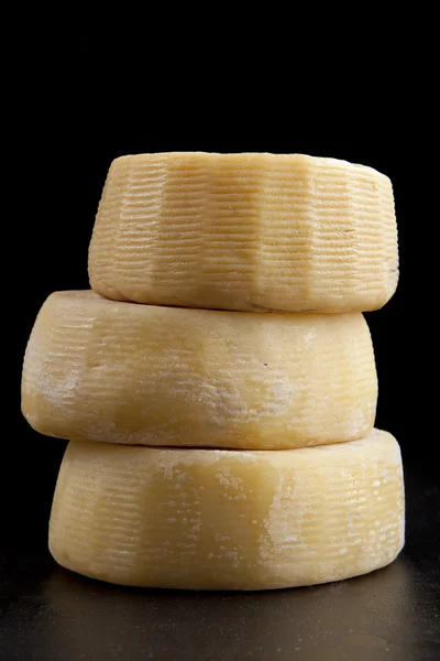 Quelques formes entières de parmesan au fromage, l'une au sommet de l'autre. sur noir — Photo