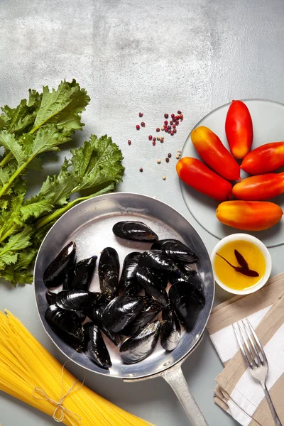 Moules dans une casserole avec les ingrédients. recette avec spaghettis et — Photo