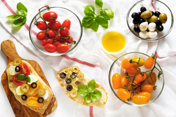 Bruschetta con tomates cherry amarillos y rojos, albahaca fresca, gre —  Fotos de Stock