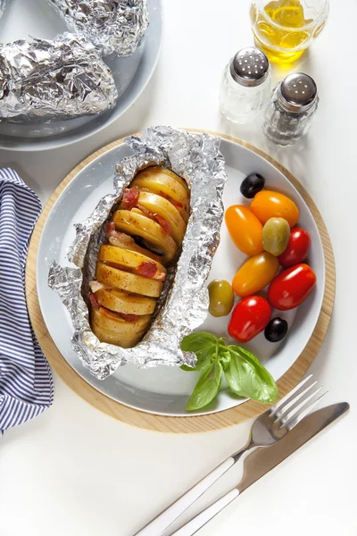 Baked potato in foil. ripe red and yellow cherry tomatoes and ol — Stock Photo, Image