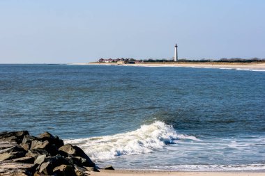 Cape May, New Jersey Deniz feneri sahilden görüldüğü gibi. Jetty, sörf, okyanus ve gökyüzü deniz fenerini çerçeveler.. 