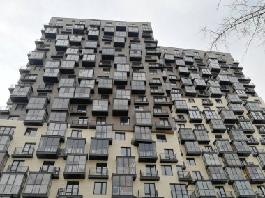 Modern bir kasaba evi, garip bir yapısı olan büyük bir bina, alışılmadık bir balkon düzeni. Cam ve pencereler.
