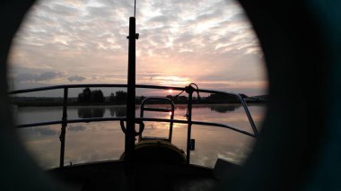 Gün batımında suda, gölde, su deposunda, bir yatta. Yatın kıç tarafından bak. Fireboard sönümleyicisindeki bir delikten