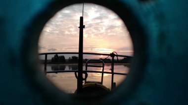 Gün batımında suda, gölde, su deposunda, bir yatta. Yatın kıç tarafından bak. Fireboard sönümleyicisindeki bir delikten