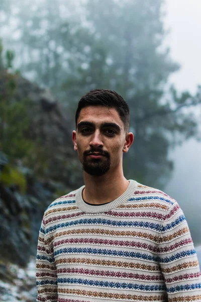 Karlı bir yolun ortasında çizgili kazak ve kot pantolon giyen bir çocuk.