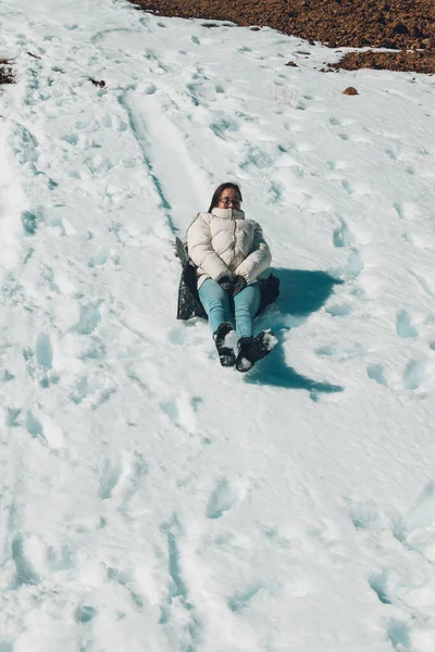 Gözlüklü ve beyaz ceketli bir kadın karlı dağlarda oynuyor.