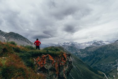 İsviçre 'deki yeşil dağlarda kırmızı ceketli bir adam.