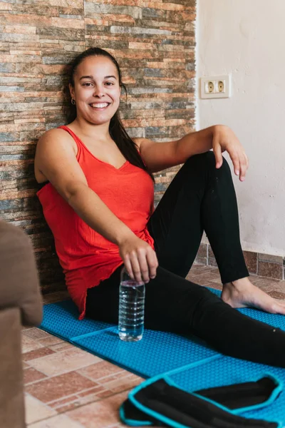 Gözlüklü ve turuncu gömlekli kız evde esneme hareketleri yapıyor.