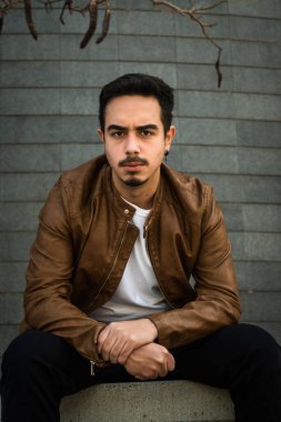 Kahverengi deri ceketli çocuk poz veriyor.