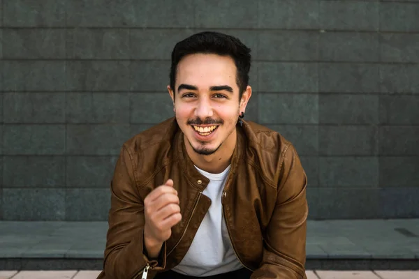 Kahverengi deri ceketli çocuk poz veriyor.