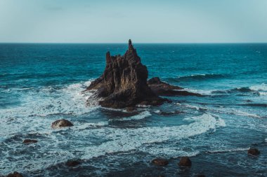 Bulutlu bir adada dağ ve deniz manzarası