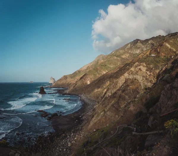 Bulutlu bir adada dağ ve deniz manzarası