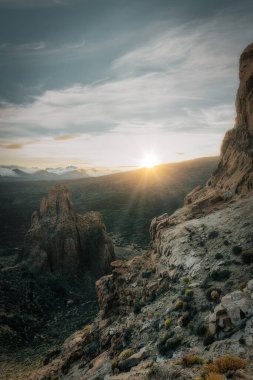 Gün batımında bir adada dağlık bir volkan manzarası.