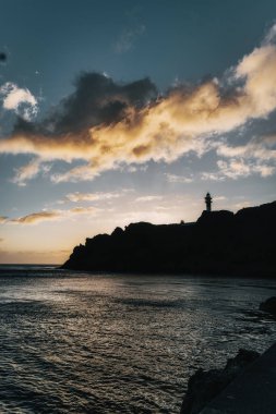 Gün batımında deniz feneriyle deniz manzarası