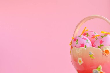 Paskalya kompozisyonu, seramik vazoda süslemeli yumurtalar, saplı ve kopyalanmış pembe arka plan, şenlikli ev dekorasyonu.