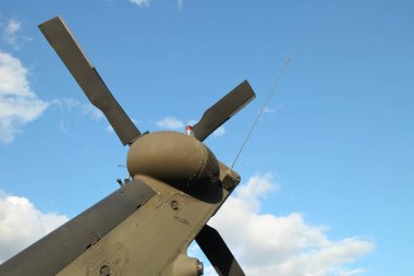 Arkadaki pervaneli kuyruk patlaması ve pervaneler mavi gökyüzü arka planına karşı askeri helikopterin arkasında.