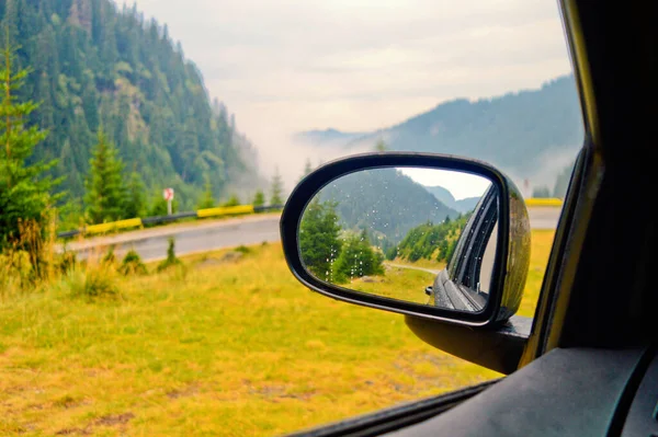 車のサイドミラーで山道の反射 旅行中の車の窓からの山々と道路の風景 — ストック写真