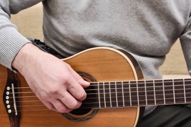 Akustik gitarla çalan adam. Enstrüman üzerinde pratik yaparken gitarist elleri ve gitar gövdesine yakından bak.