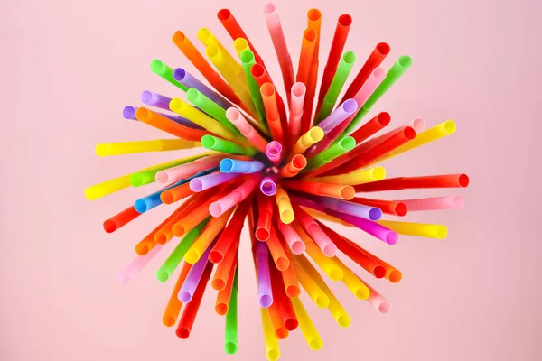 Pembe arka planda çok renkli plastik pipetlerin üst görünümü.