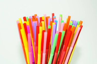 Beyaz arka planda çok renkli plastik pipetler. Kokteyl ve içki partisi için renkli aksesuar ve dekorasyon.