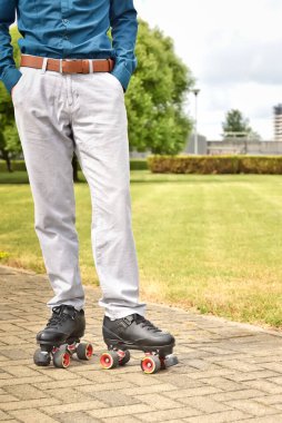Şehir sokaklarında buz pateni ve açık hava aktiviteleri yaparken pantolonlu ve patenli bir adamın bacakları. Paten kaymak hafta sonları vakit geçirmek için sağlıklı bir spor hobisidir..