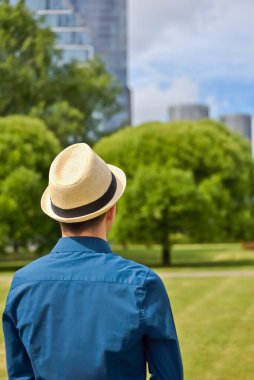 İş görüşmesinden önce çalışan şapkalı genç bir adam bir ofis binasına bakar ve işi ve kariyeri düşünür..