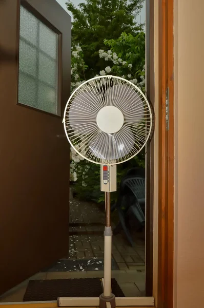 Electric floor fan stands at the door of the house for cooling in hot weather