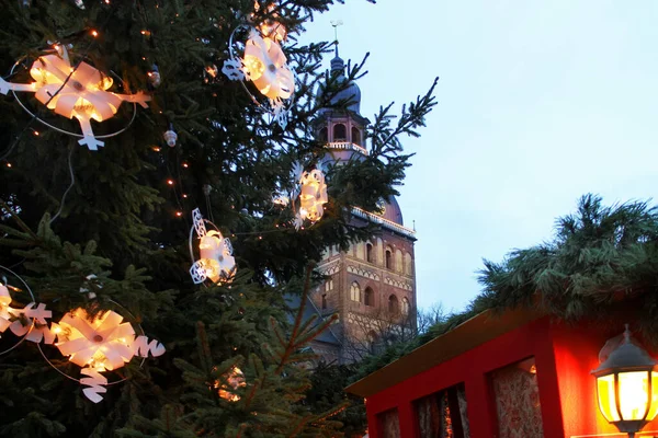 Yılbaşı arifesinde, Letonya 'daki Riga Kubbesi Katedrali' nin arka planında süslü çelenk ışıkları olan Noel ağacı.