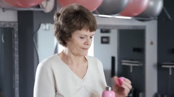 Portrét starší ženy ve fitness místnosti pitné vody — Stock video
