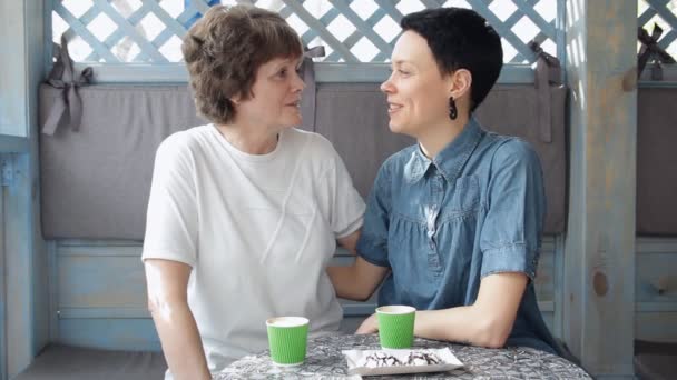 Senior mother and young daughter talking on sofa, laughing and having coffee together. Happy family. — Stock Video