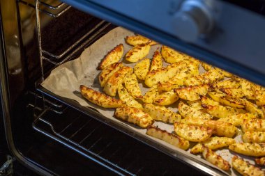 Baharat ve otlarla fırın fırınında pişirilmiş dalgalı patatesleri yakından izleyin.