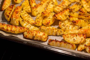 Baharat ve otlarla fırın fırınında pişirilmiş dalgalı patatesleri yakından izleyin.