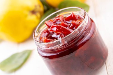 Eski ahşap bir arka planda cam kavanozda ev yapımı ayva reçeli. Ayva reçelli taze meyve ve yapraklar..