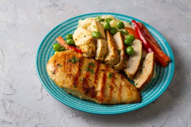 Izgara tavuk göğsü dilimleri patates püresi ve sebzeyle servis edilir..