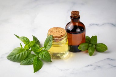 Fesleğen yağı ve taze yapraklar ahşap masada, yakın plan.