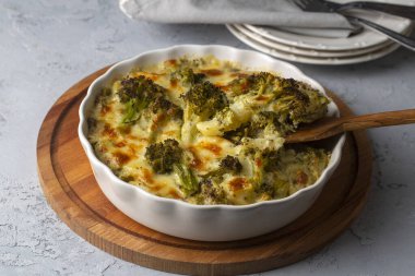 Casserole Cauliflower and broccoli baked with cheese sauce in a pot close-up on a wooden table. Horizontal top view from above. Broccoli gratin.