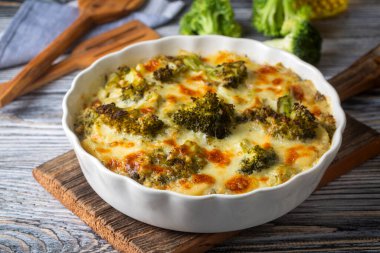Casserole Cauliflower and broccoli baked with cheese sauce in a pot close-up on a wooden table. Horizontal top view from above. Broccoli gratin.