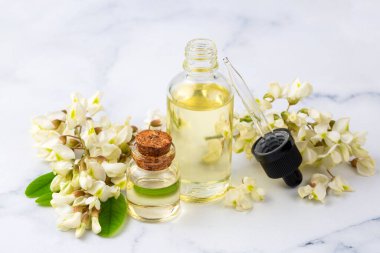 Robinia (sahte akasya) esaslı yağ (çare, özü) şişesi taze akasya çiçekleri ile