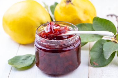 Homemade quince jam in a glass jar on an old wooden background. Fresh quince fruits and leaves and quince jam. (Turkish name; ayva receli)