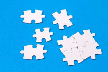 Missing jigsaw puzzle pieces. Business concept. Fragment of a folded white jigsaw puzzle and a pile of uncombed puzzle elements against