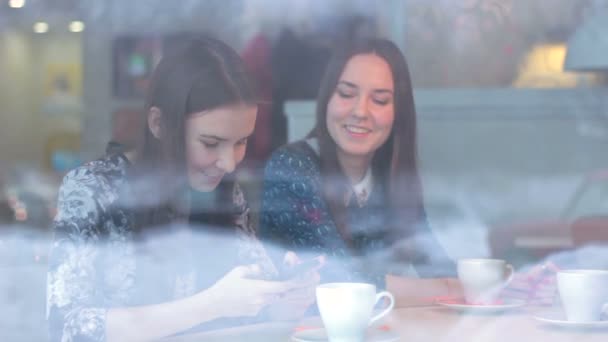 Schönes Mädchen zeigt Smartphone-Freundin im Café — Stockvideo