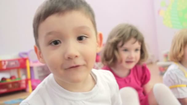 Bambini seduti agitando le mani alla telecamera. all'asilo nido — Video Stock