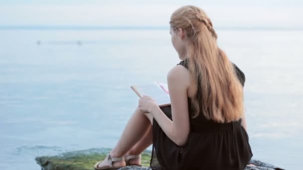 Einsames rothaariges Mädchen liest Buch am Fluss — Stockvideo