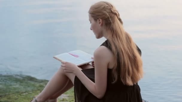 Alleen roodharige meisje leesboek op rivier — Stockvideo