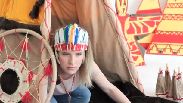 Jeune fille blonde en costume indien amérindien rampant de wigwam — Video