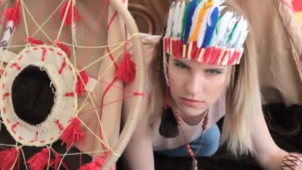 Jeune fille blonde en costume indien amérindien rampant de wigwam — Video