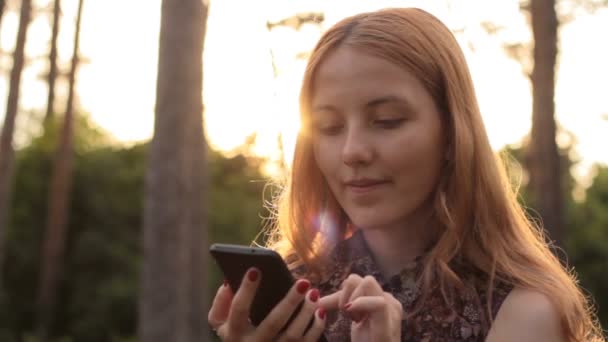 Jeune fille aux cheveux roux utilisant un téléphone portable — Video